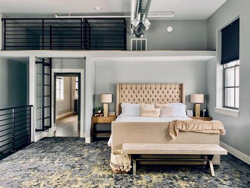 Hotel bedroom with stairs and balcony.