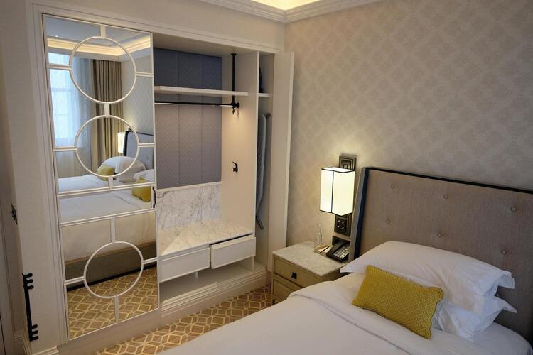 Hotel bed with nightstand and mirror.